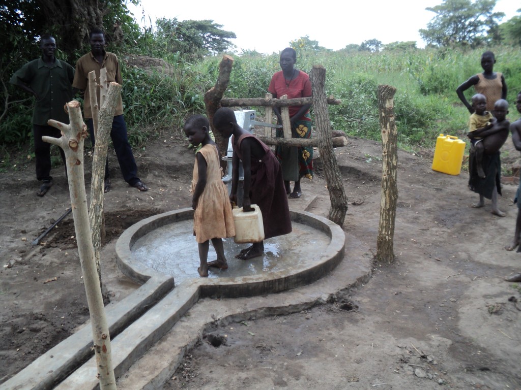 Mary Akello 30 years pumping water as her neighbours children fetches at Aloborom well